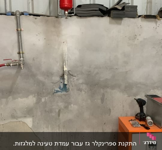 מטף כיבוי אש תלוי על קיר מתכת במבנה תעשייתי